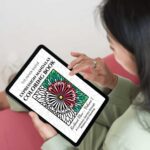 Woman holding a tablet with the Expression Mandalas Coloring Book by The Inner Seeker displayed on screen