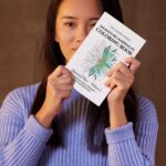 Woman holding Signature Mandalas Coloring Book – Botanical Flow by The Inner Seeker
