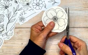 Hands cutting a paper flower during a slow, mindful creative process on a wooden table