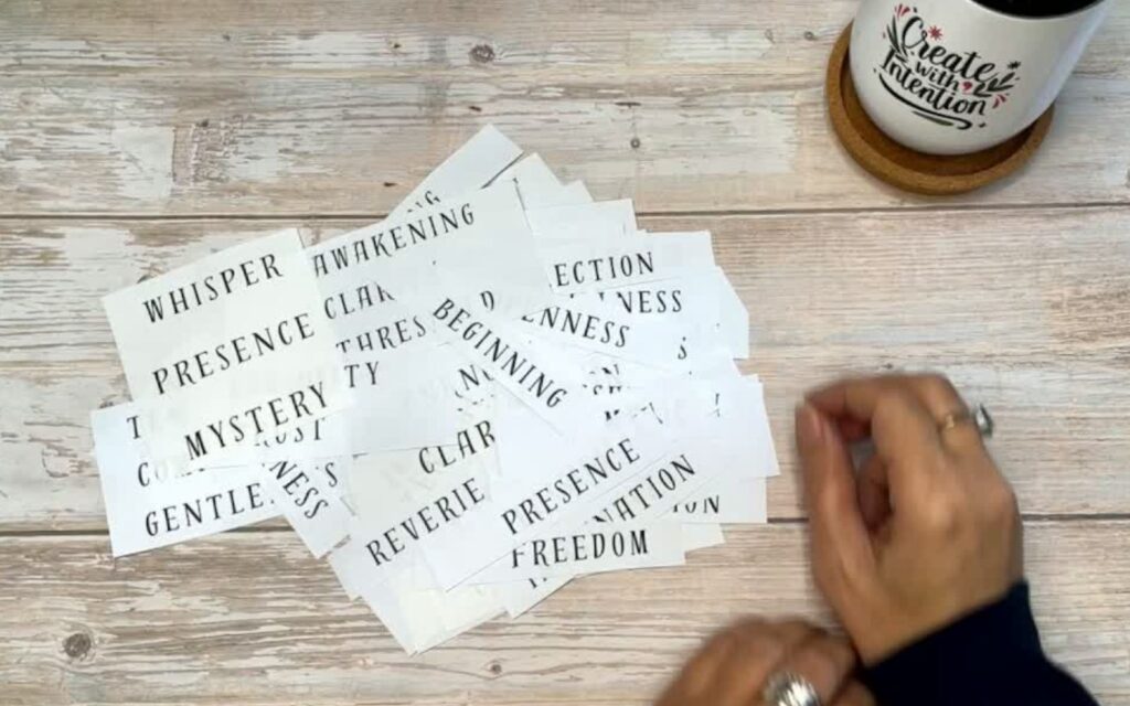 A spread of printed words on a wooden table used for a mindful creative practice focused on presence, intuition, and inner reflection.