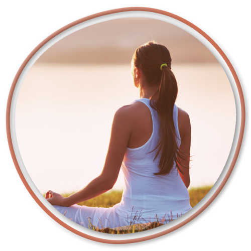 Woman meditating by a lake during sunset